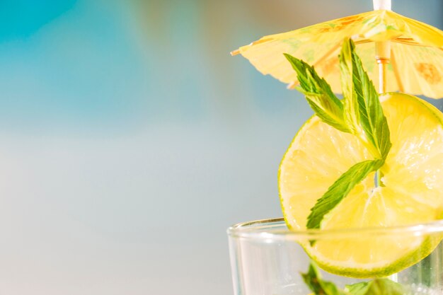 Tranche de citron vert avec feuille de menthe poivrée sous un parapluie