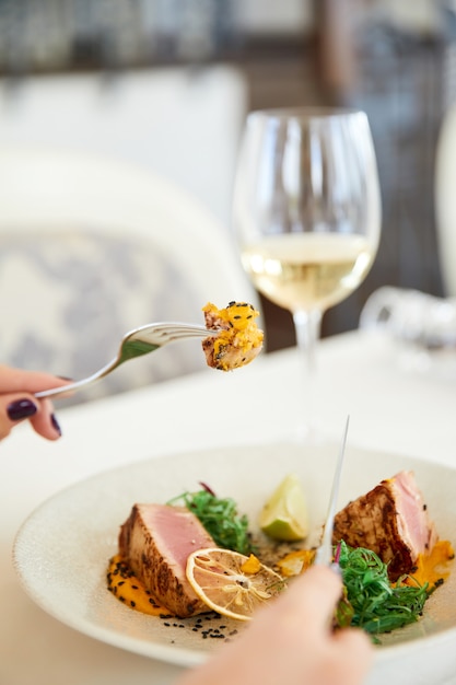 Photo gratuite tranche d'un délicieux repas de thon avec un verre de vin blanc au restaurant