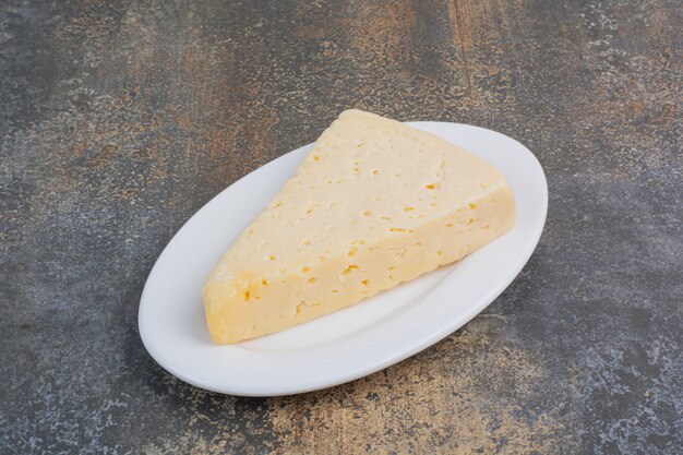 Tranche de fromage jaune sur plaque blanche