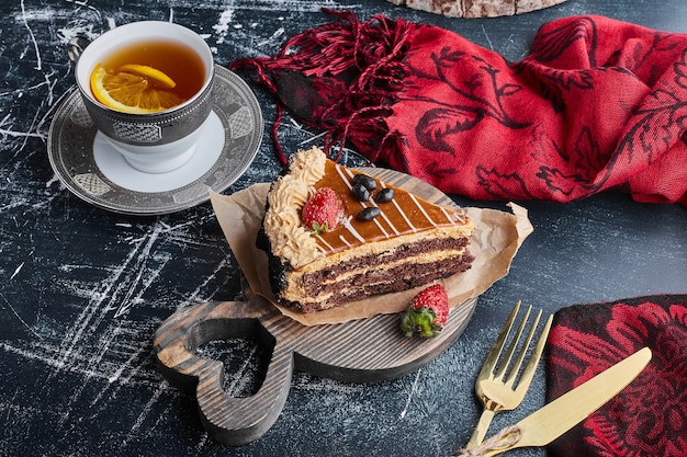 Une tranche de gâteau au chocolat et au caramel avec une tasse de thé.