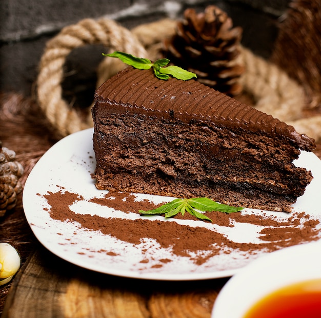 Tranche de gâteau au chocolat et cacao servie avec des feuilles de menthe