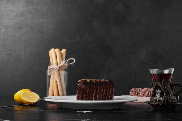 Une tranche de gâteau au chocolat dans une assiette blanche avec un verre de thé.