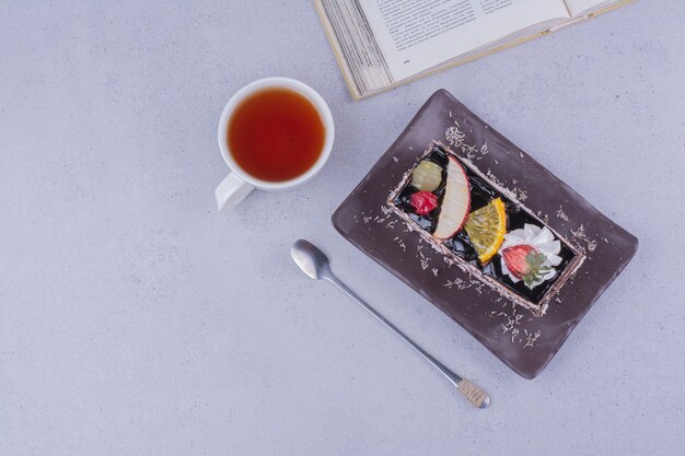 Une tranche de gâteau au chocolat avec des fruits et une tasse de boisson.