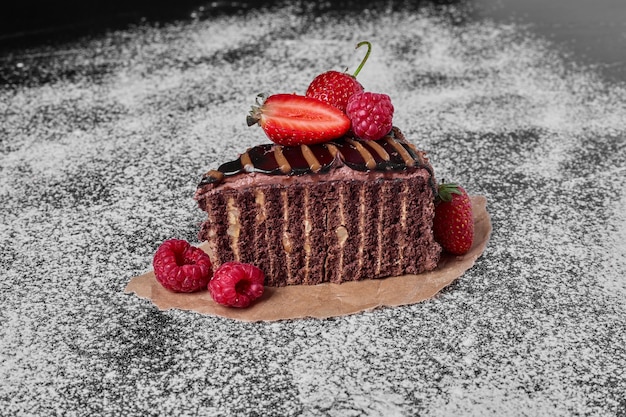 Tranche de gâteau au chocolat sur un plateau en bois.