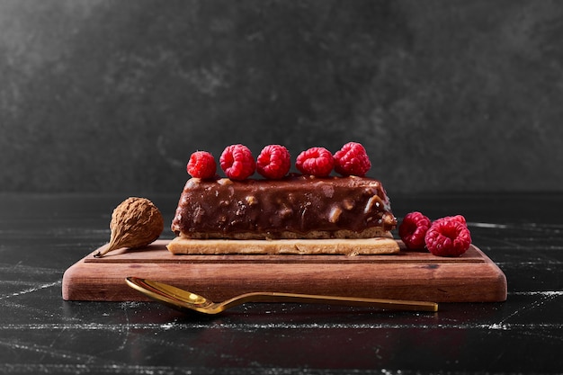 Tranche de gâteau au chocolat sur un plateau en bois.