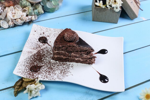Une tranche de gâteau au chocolat avec de la poudre de cacao.