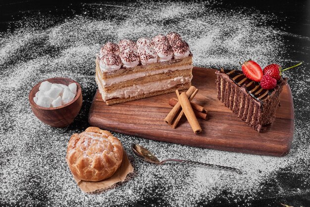 Tranche de gâteau au chocolat avec tiramisu sur un plateau en bois.