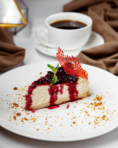 Tranche de gâteau au fromage au cassis garnie de cassis et de sirop