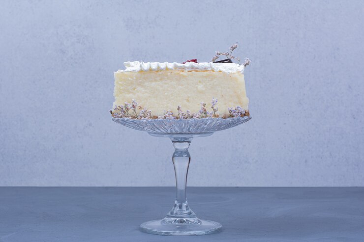 Photo gratuit une tranche de gâteau au fromage dans une soucoupe en verre sur fond bleu