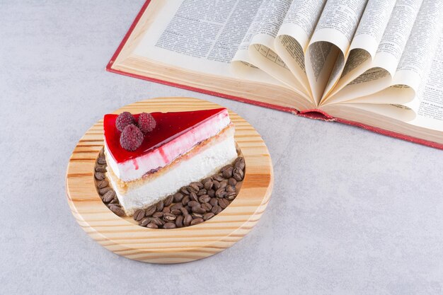 Tranche de gâteau au fromage avec grains de café et livre.