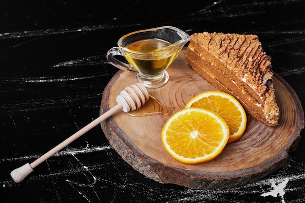 Photo gratuite une tranche de gâteau au miel avec des tranches d'orange et du sirop