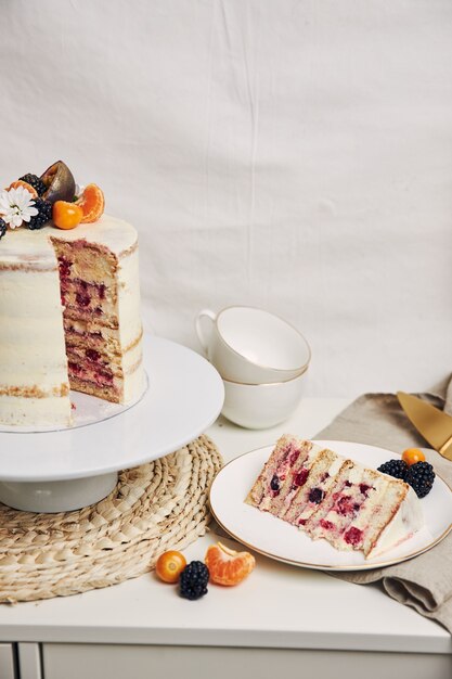 Tranche d'un gâteau aux baies et fruits de la passion sur la table derrière un fond blanc