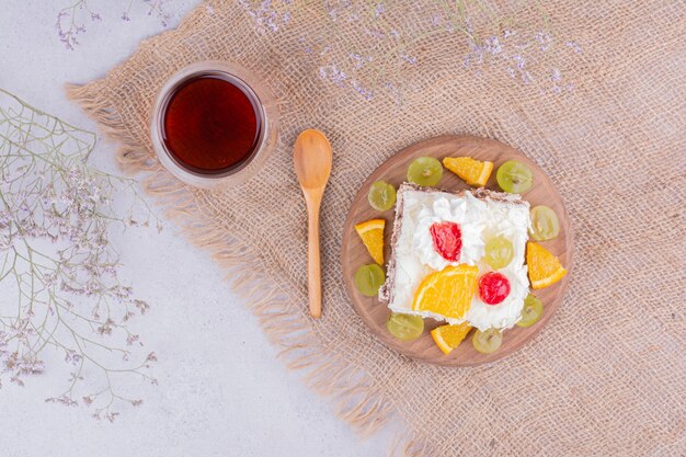 Une tranche de gâteau aux fruits avec crème fouettée et thé