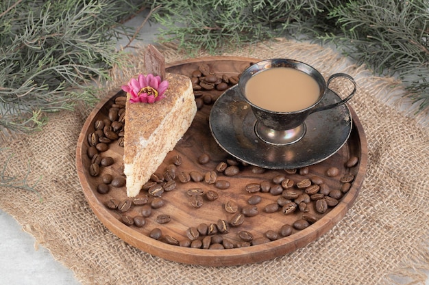 Tranche de gâteau, café et grains de café sur une plaque en bois