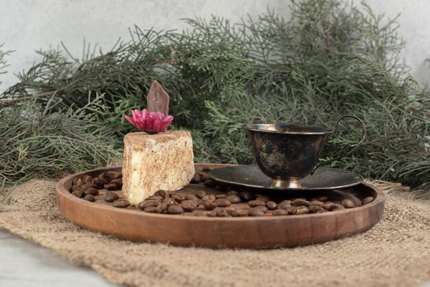 Tranche de gâteau, café et grains de café sur une plaque en bois