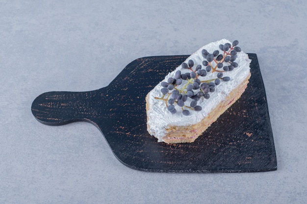 Tranche de gâteau crémeux frais aux myrtilles sur une planche à découper en bois noir