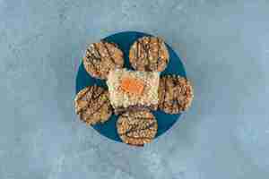 Photo gratuite une tranche de gâteau entouré de cookies sur un tableau bleu sur une surface en marbre