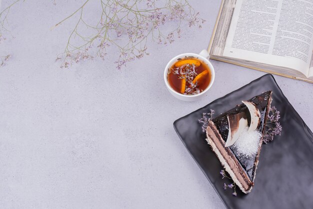 Une tranche de gâteau ganache au chocolat avec une tasse de tisane.