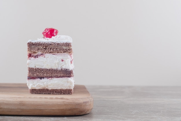 Tranche de gâteau garni de cerises sur une planche sur marbre