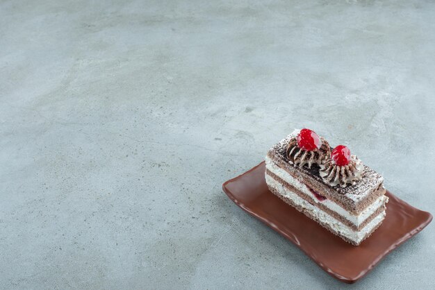 Tranche de gâteau savoureux sur plaque brune.