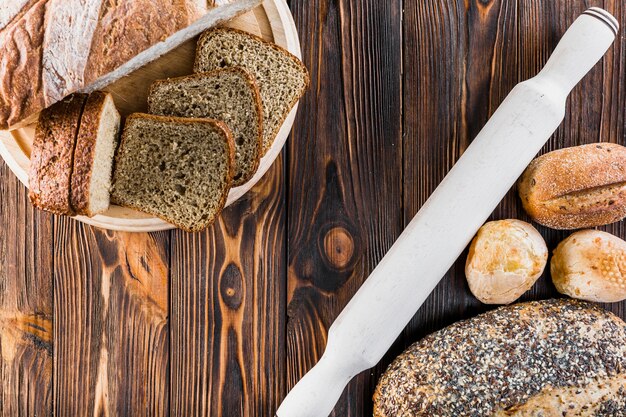 Tranche et miches de pain avec rouleau à pâtisserie sur un bureau en bois