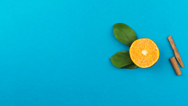 Tranche d&#39;orange fraîche près de la cannelle et du feuillage