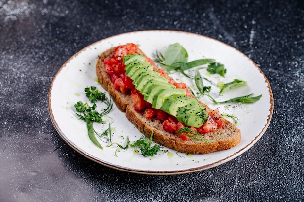 Une tranche de pain noir avec des cubes de tomate et des tranches de concombre.