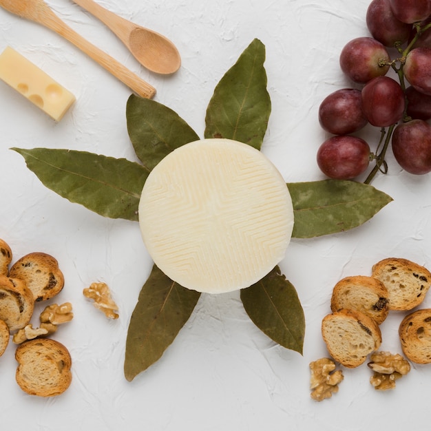 Photo gratuite tranche de pain; noyer; les raisins; feuilles de laurier et cuillère en bois au fromage espagnol manchego