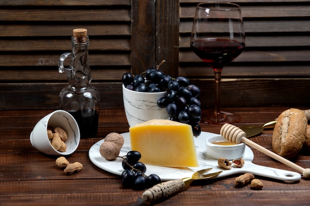 Tranche de parmesan servie avec du vin et du raisin