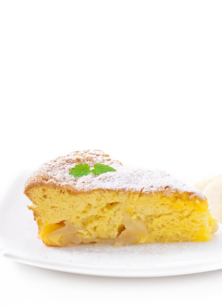 Tranche de tarte aux pommes sur une assiette décorée de feuilles de menthe