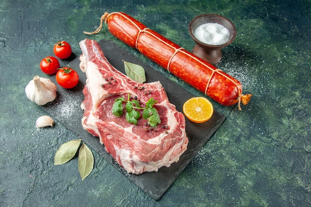 Tranche de viande fraîche vue de moitié avec des tomates et du poivre sur une surface bleu foncé