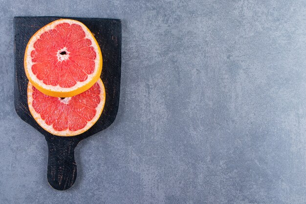 Trancher le pamplemousse sur une planche à découper sur la surface en marbre