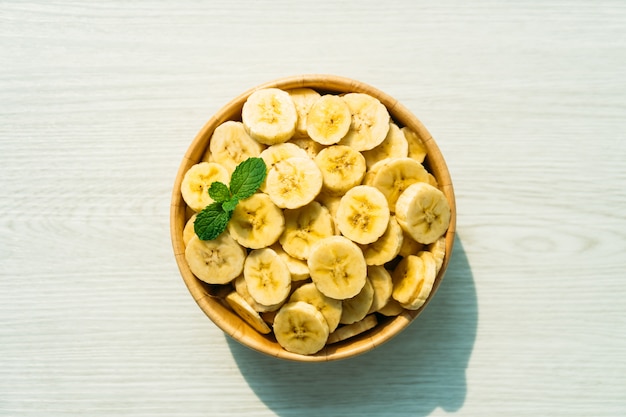 Tranches de bananes jaunes crues dans un bol en bois