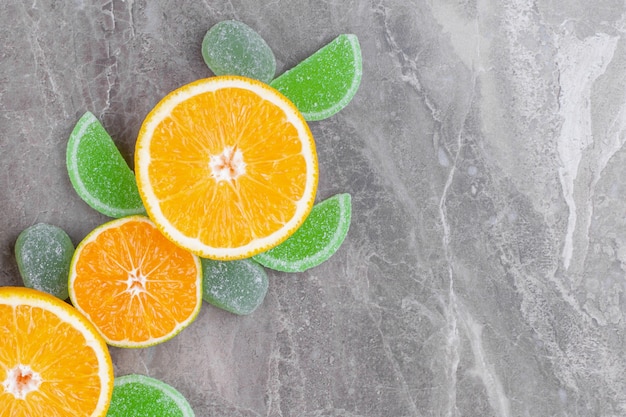 Tranches de bonbons à la marmelade juteuse orange et verte sur une surface en marbre.