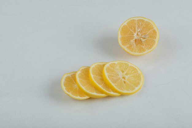 Tranches de citron juteux sur une surface blanche.