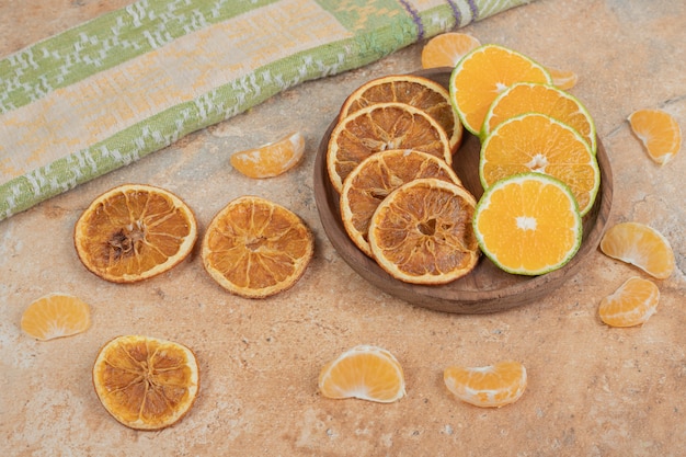 Tranches de citron, mandarine et orange séchée sur plaque en bois.