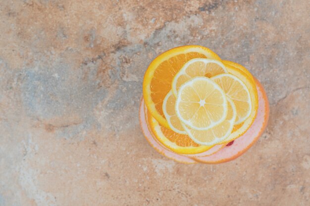 Tranches de citron, d'orange et de pamplemousse juteuses sur fond de marbre.