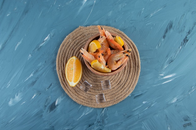 Tranches de citrons et de crevettes dans un bol sur un dessous de plat , sur le fond de marbre.