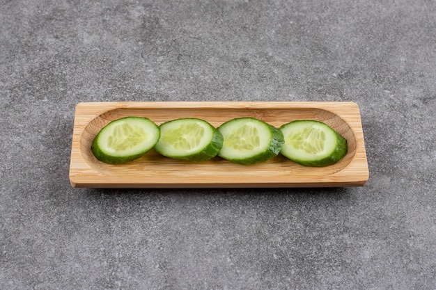 Tranches de concombre frais sur planche de bois sur une surface grise