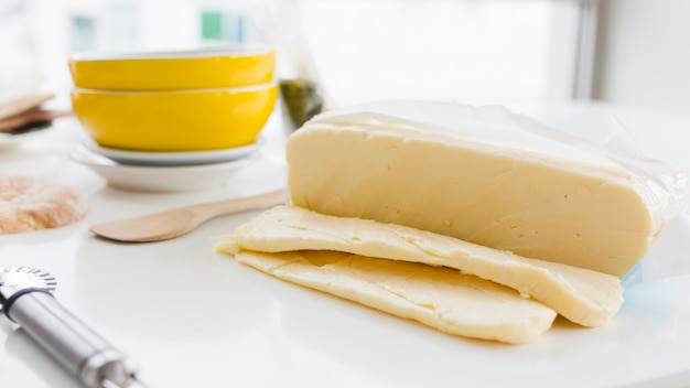 Tranches de fromage cheddar sur un bureau blanc avec des bols