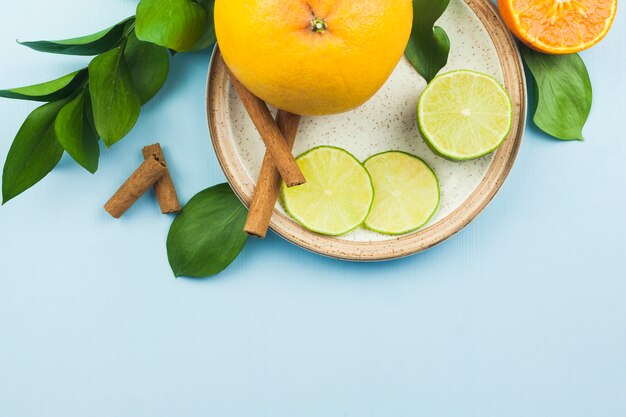 Tranches de fruits exotiques près de la cannelle sur une plaque avec un feuillage