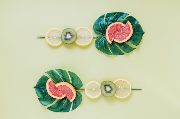 Photo gratuite tranches de fruits sur feuilles vertes