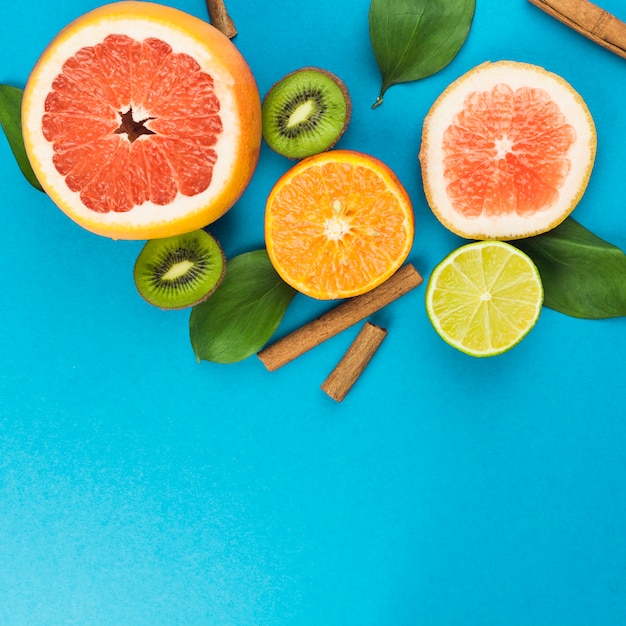 Tranches de fruits frais près de cannelle et de feuillage