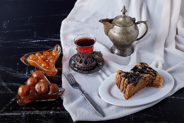 Tranches de gâteau dans une assiette blanche avec du sirop de chocolat et du thé.