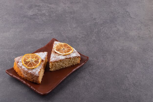 Tranches de gâteau fait maison frais sur une plaque sur une surface grise