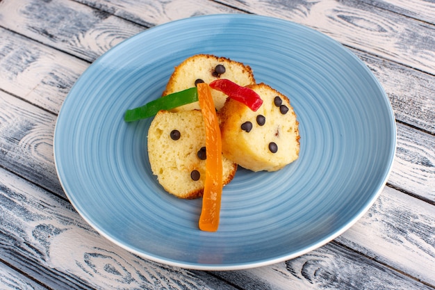 Tranches de gâteau à l'intérieur de la plaque bleue avec des chips de chocolat et de la marmelade sur un bureau gris rustique