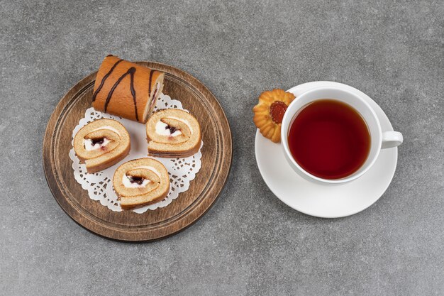 Tranches de gâteau sucré sur planche de bois avec tasse de thé