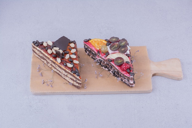 Tranches de gâteau triangle au chocolat et fruits sur une planche de bois