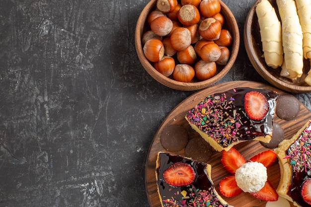 Tranches de gâteau vue de dessus avec des noix et des biscuits sur une surface sombre