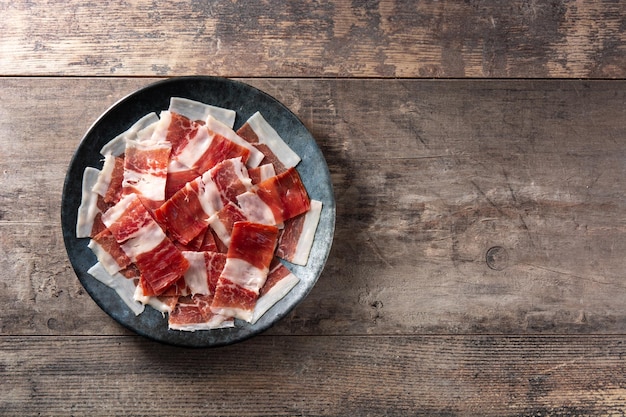 Photo gratuite tranches de jambon serrano espagnol sur plaque noire sur table en bois